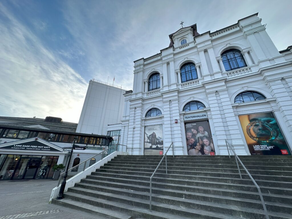Outside view of Rogaland Theater a large white brick building with steps leading up to it.