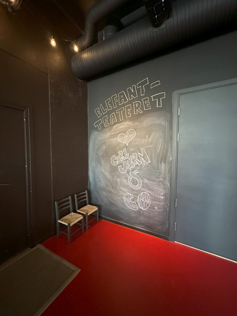 A sign in chalk on a black wall reads "Elefant-Teateret (heart sign) Carl Jorn & Co"